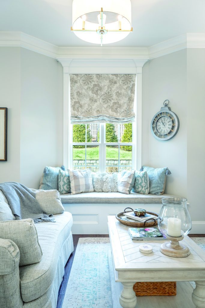 Bright living room featuring a gray sofa, patterned cushions, and a white coffee table with decor items. A window seat perfectly frames the lush garden view outside. Discover tips for creating a home you love with these stylish elements and thoughtful design choices.
