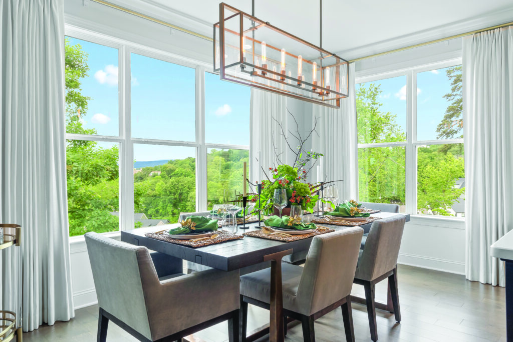 Chattanooga dining room with linen traversing draperies framing large windows, a dark wood table, gray chairs, and garden views